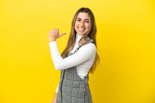 Giovane donna caucasica isolata su sfondo giallo orgogliosa e soddisfatta di sé