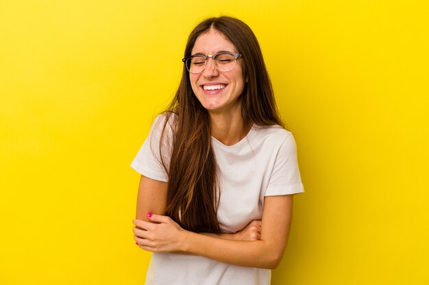 Giovane donna caucasica isolata su sfondo giallo ridendo e divertendosi.