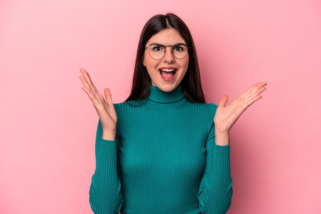 Giovane donna caucasica isolata su sfondo rosa che celebra una vittoria o un successo è sorpreso e scioccato