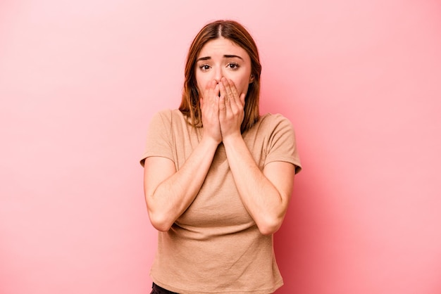 Giovane donna caucasica isolata su sfondo rosa che copre la bocca con le mani che sembrano preoccupate