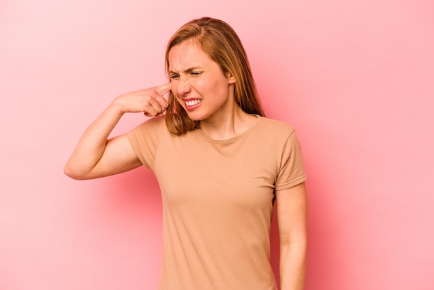 Giovane donna caucasica isolata su sfondo rosa che copre le orecchie con le mani