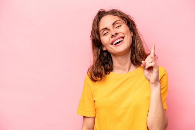 Giovane donna caucasica isolata su sfondo rosa che mostra il numero uno con il dito