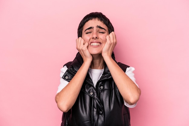 Giovane donna caucasica isolata su sfondo rosa che piange, insoddisfatta di qualcosa, agonia e concetto di confusione.