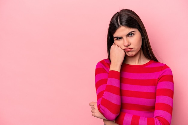 Giovane donna caucasica isolata su sfondo rosa che si sente triste e pensierosa guardando lo spazio della copia