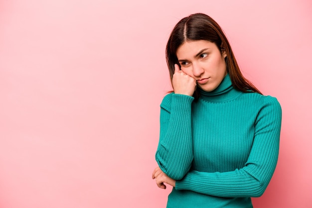 Giovane donna caucasica isolata su sfondo rosa che si sente triste e pensierosa guardando lo spazio della copia