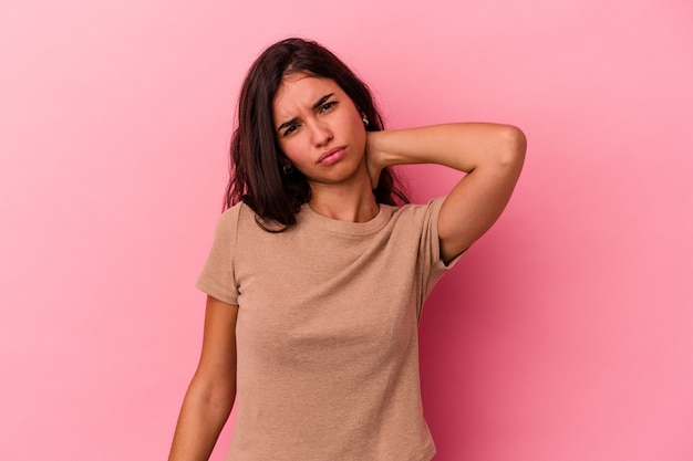 Giovane donna caucasica isolata su sfondo rosa con dolore al collo dovuto allo stress, massaggiandolo e toccandolo con la mano.