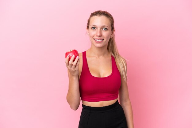 Giovane donna caucasica isolata su sfondo rosa con una mela
