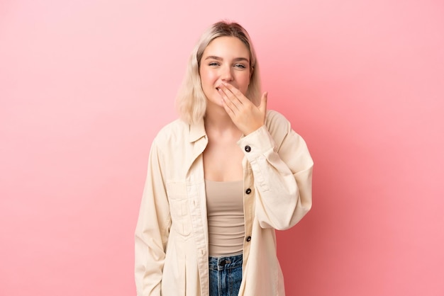 Giovane donna caucasica isolata su sfondo rosa felice e sorridente che copre la bocca con la mano