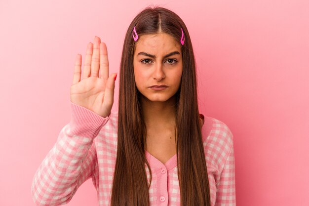 Giovane donna caucasica isolata su sfondo rosa in piedi con la mano tesa che mostra il segnale di stop, impedendoti.