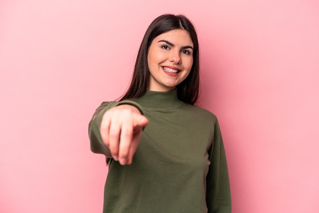 Giovane donna caucasica isolata su sfondo rosa sorrisi allegri che puntano in avanti