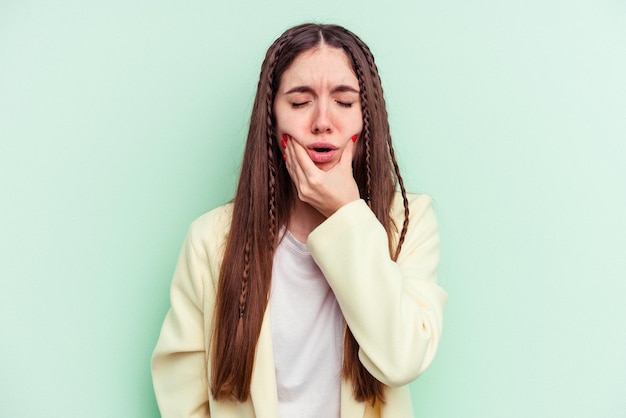 Giovane donna caucasica isolata su sfondo verde con un forte dolore ai denti, dolore molare.