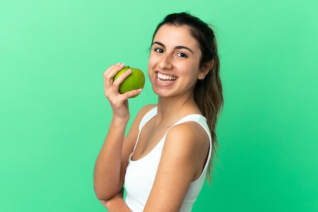 Giovane donna caucasica isolata su sfondo verde, mangiare una mela