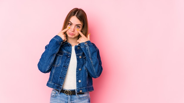 Giovane donna caucasica isolata sul muro rosa piangendo, insoddisfatta di qualcosa, agonia e concetto di confusione.