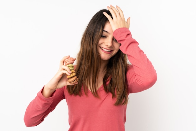 Giovane donna caucasica isolata sul rosa che tiene i macarons francesi variopinti