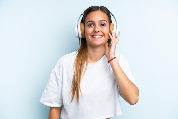 Giovane donna caucasica isolata sulla musica d'ascolto del fondo blu