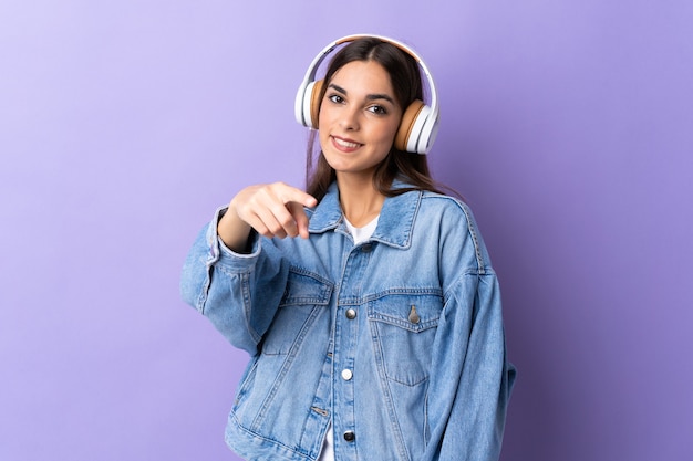 Giovane donna caucasica isolata sulla musica d'ascolto della parete viola