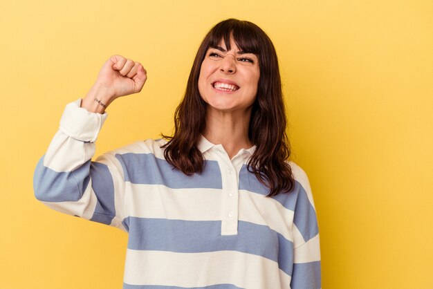 Giovane donna caucasica isolata sulla parete gialla che celebra una vittoria, passione ed entusiasmo, felice espressione