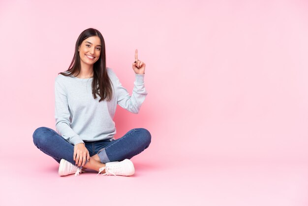 Giovane donna caucasica isolata sulla parete rosa che mostra e che solleva un dito nel segno del meglio