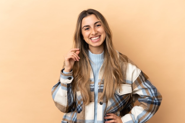 Giovane donna caucasica isolata sulla risata beige del fondo