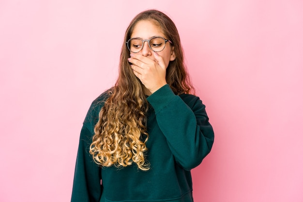 Giovane donna caucasica premurosa che guarda a uno spazio copia che copre la bocca con la mano.