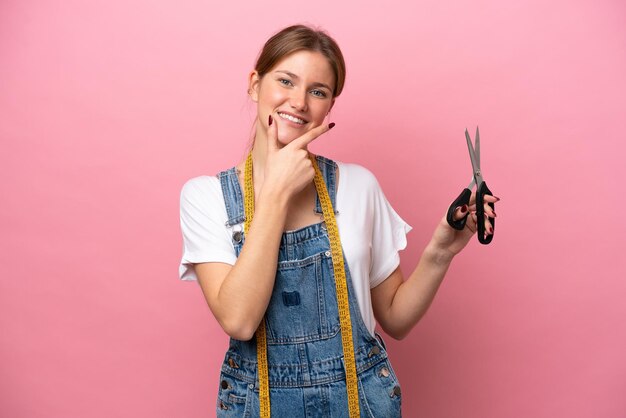 Giovane donna caucasica sarta isolata su sfondo rosa felice e sorridente