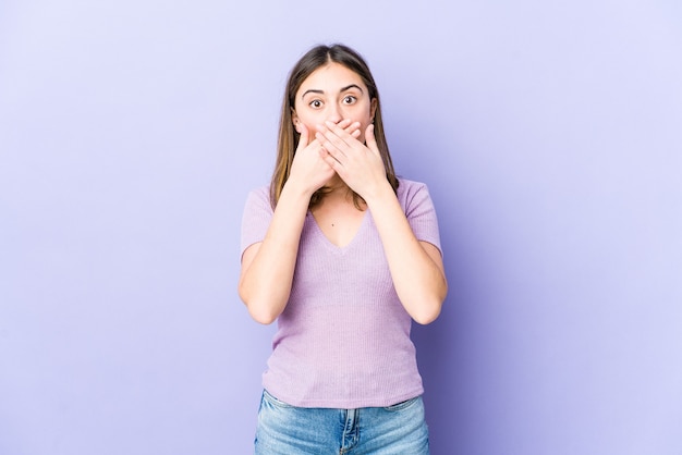 Giovane donna caucasica scioccata che copre la bocca con le mani.