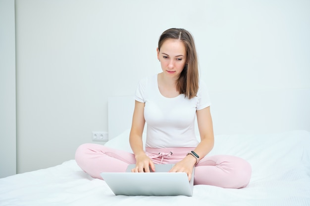 Giovane donna caucasica seduto sul divano e utilizzando il computer portatile a casa