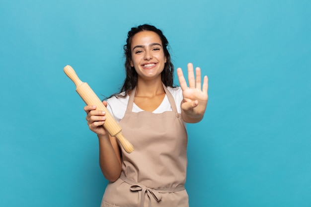 Giovane donna caucasica sorridente e dall'aspetto amichevole, mostrando il numero quattro o il quarto con la mano in avanti, il conto alla rovescia