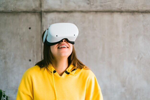 Giovane donna caucasica sorridente utilizzando auricolare Vr, alzando lo sguardo nella realtà virtuale.