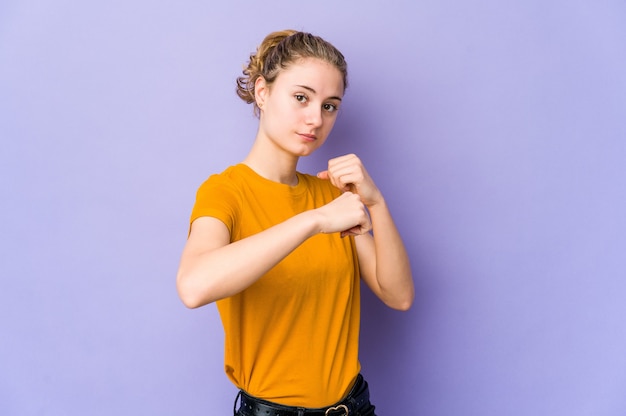 Giovane donna caucasica su sfondo viola lanciando un pugno, rabbia, combattimenti a causa di un argomento, boxe.