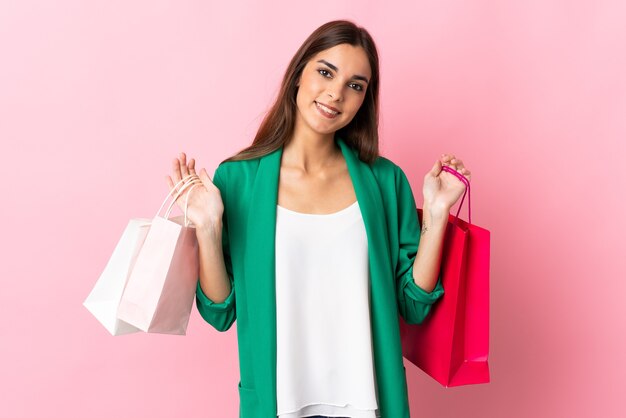 Giovane donna caucasica sui sacchetti della spesa rosa della tenuta e sul sorridere