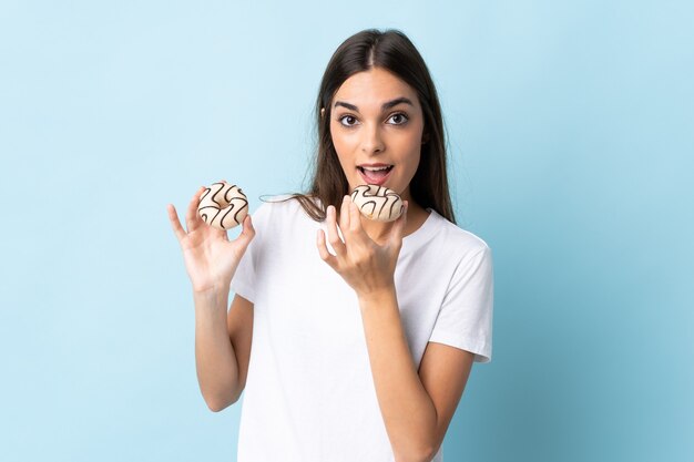 Giovane donna caucasica sull'azzurro che mangia una ciambella