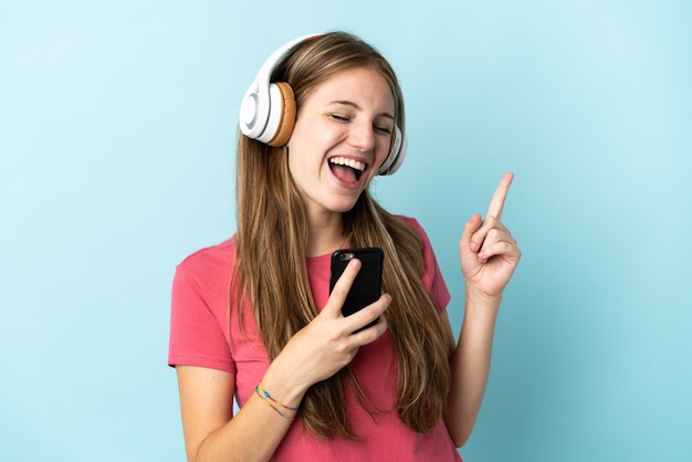 Giovane donna caucasica sulla musica d'ascolto blu con un cellulare e cantando