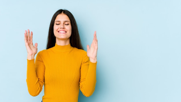 Giovane donna caucasica sulla parete blu allegra che ride molto