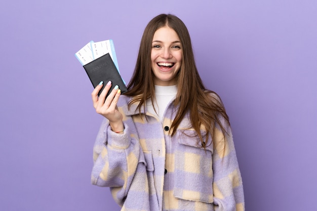 Giovane donna caucasica sulla parete viola felice in vacanza con passaporto e biglietti aerei