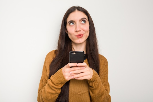 Giovane donna caucasica tramite telefono cellulare isolato su sfondo bianco