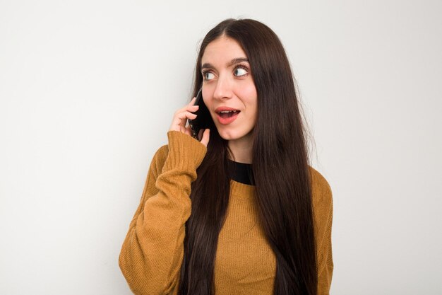 Giovane donna caucasica tramite telefono cellulare isolato su sfondo bianco