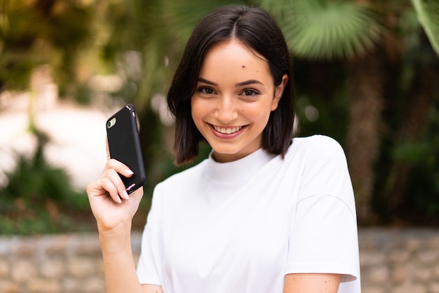 Giovane donna caucasica utilizzando un telefono all'aperto