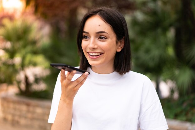 Giovane donna caucasica utilizzando un telefono all'aperto