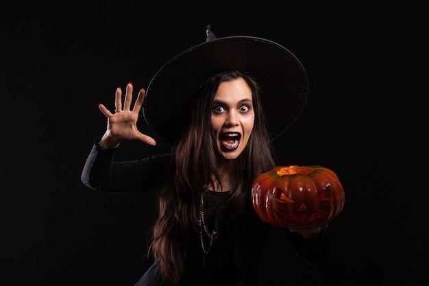 Giovane donna caucasica vestita come una strega e urlando alla telecamera. Abito di Halloween. Signora spaventosa ad Halloween.