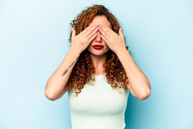 Giovane donna caucasica zenzero isolata su sfondo blu paura che copre gli occhi con le mani