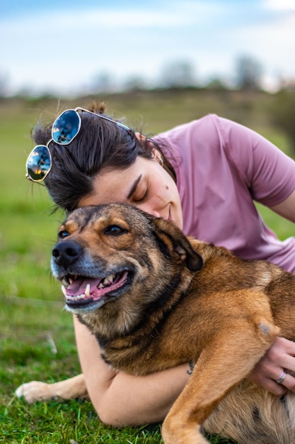 Giovane donna che accarezza e si diverte con il suo cane in campagna