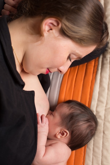 Giovane donna che allatta al seno il suo bambino appena nato