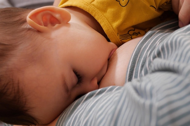 Giovane donna che allatta il suo bambino a casa Il latte materno è una medicina naturale per il bambino Il concetto di legame del giorno della madre con l'allattamento del neonato