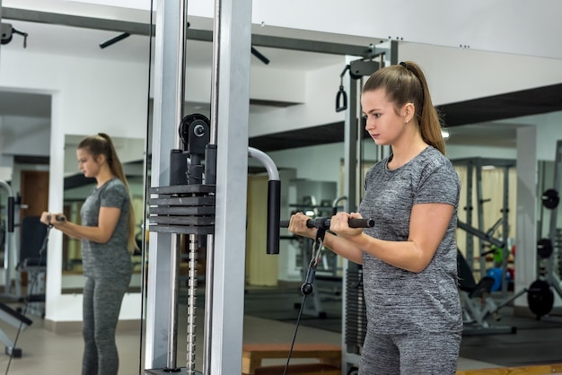 Giovane donna che alza il bilanciere in palestra