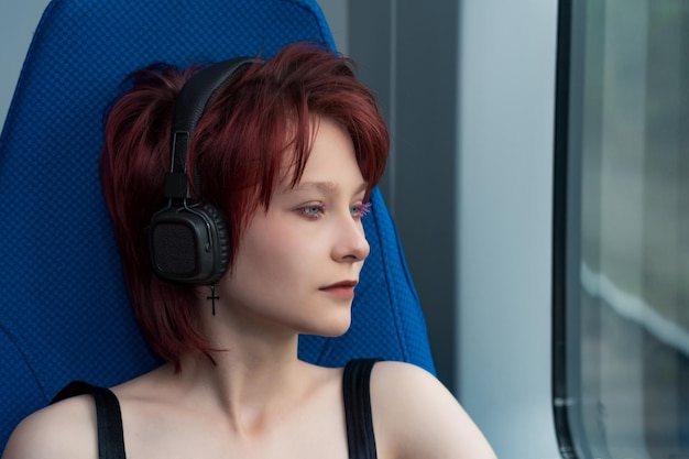 Giovane donna che ascolta la musica con le cuffie mentre si guida su un treno ad alta velocità