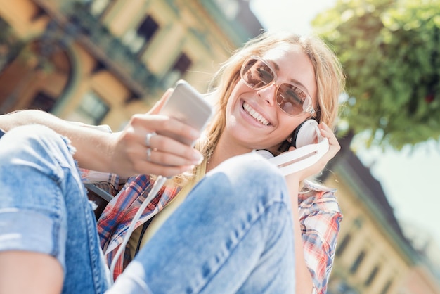 Giovane donna che ascolta la musica su uno smartphone in città.
