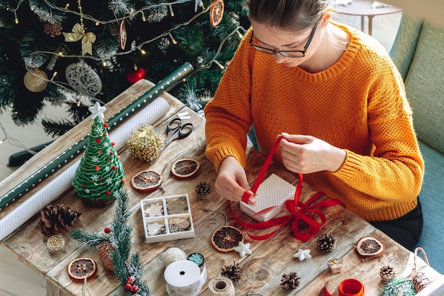 Giovane donna che avvolge il regalo di Natale sul tavolo