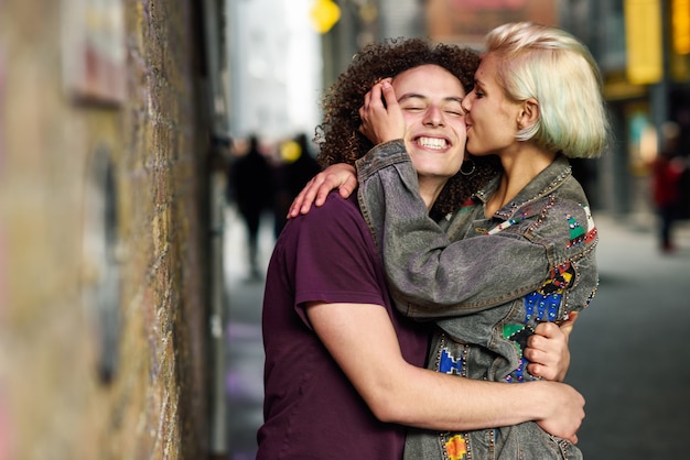 Giovane donna che bacia il suo ragazzo nel fondo urbano su una tipica strada di Londra