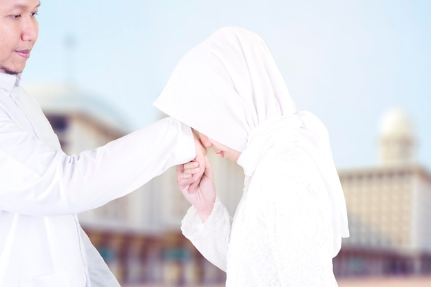 Giovane donna che bacia le mani del marito a Eid